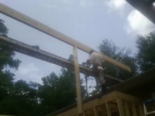 Carpenter setting a ridge beam over a new addition frame — Ice Dam Removal by Roofing Brothers in Booneville