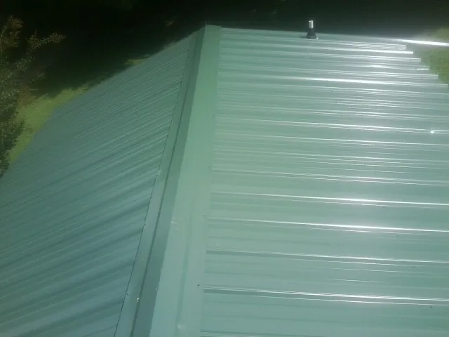 New green metal panels meeting at the ridge of a roof — Flat Roof Repair work by our crew in Booneville