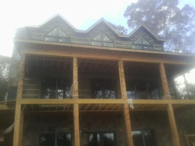 Dormers and porch framing on a large log home under construction — Roof Coating work by our crew in Booneville