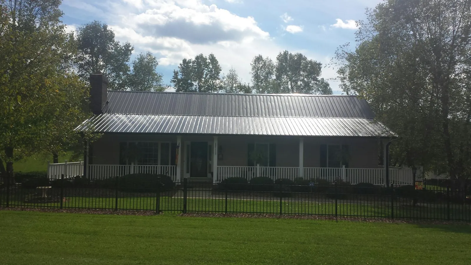Gray metal roof on a brick ranch with a full width front porch — Gutter Guard Installation work by our crew in Booneville