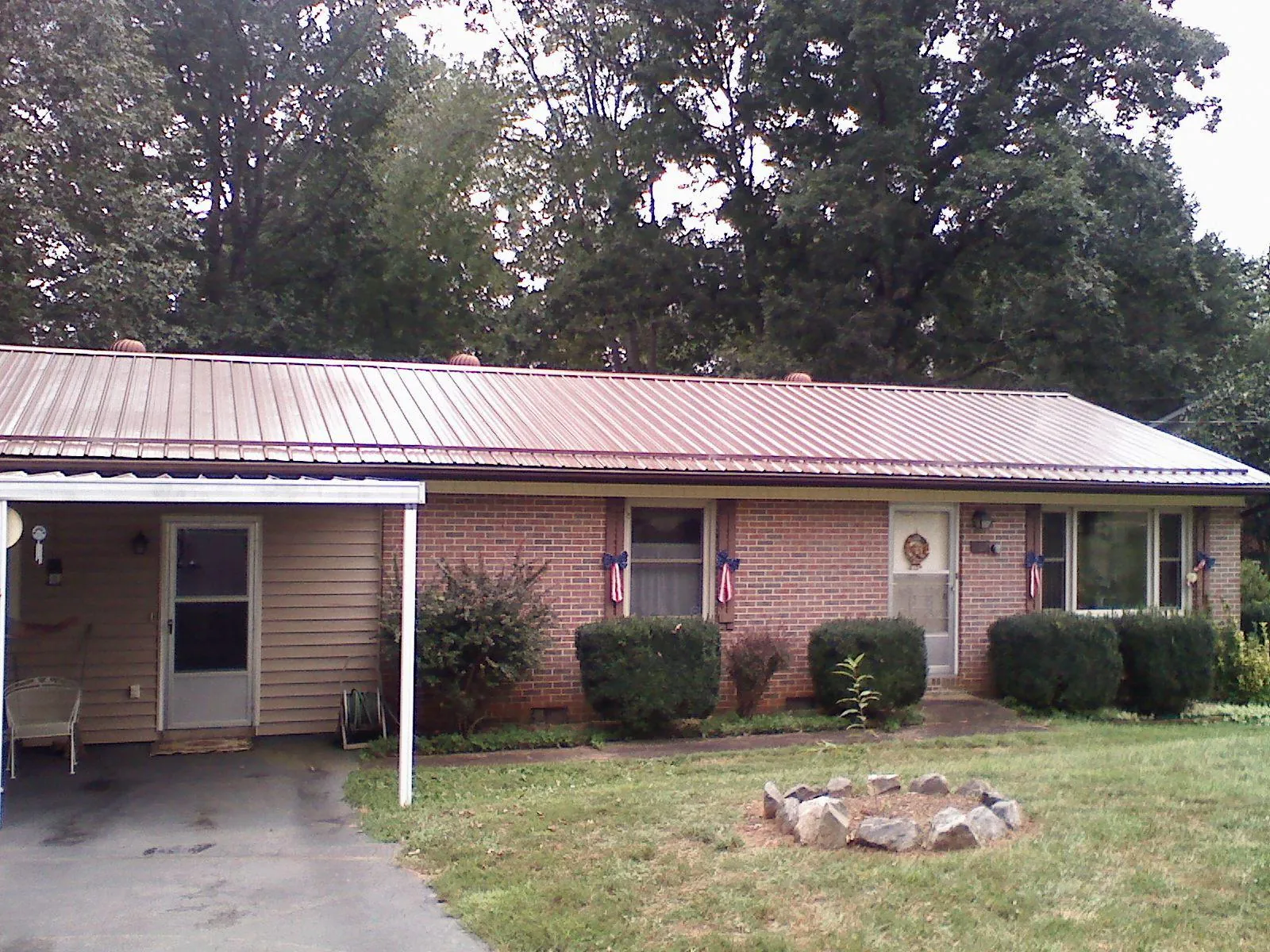Bronze metal roof and carport on a brick ranch home — Roof Repair work by our crew in Booneville